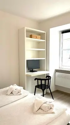 a bedroom with two beds with a desk and a chair at Life Studio & City Bike in Bolzano