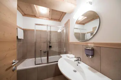 a bathroom with a tub and a sink and a mirror at Hotel Alpenhof in Ultimo