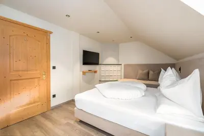 a bedroom with a large white bed with white pillows at Wellness Residence Villa Leck in Selva di Val Gardena