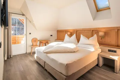 a bedroom with a large white bed and a window at Wellness Residence Villa Leck in Selva di Val Gardena