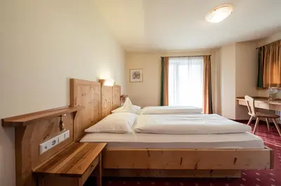 a bedroom with two beds and a desk in it at Hotel Seerast in Ultimo