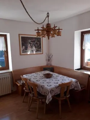 a dining room with a table and chairs and a chandelier at Appartamento Vista Dolomiti by GoNewLocation in Moena