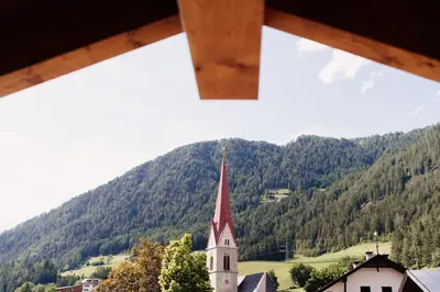 a view of a church with a mountain in the background at Hotel Gasthaus Post in Campo di Trens