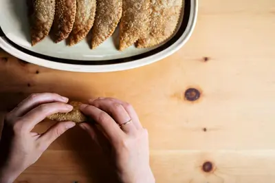 a person holding a cookie in front of a plate of cookies at Hotel Gasthaus Post in Campo di Trens