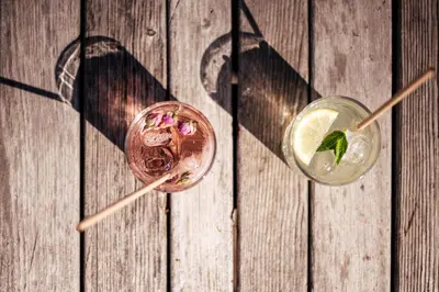 two drinks sitting on a wooden table with their shadows at Hotel Gasthaus Post in Campo di Trens