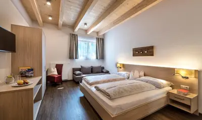 a bedroom with a large bed and a couch at Hotel Gasthaus Post in Campo di Trens
