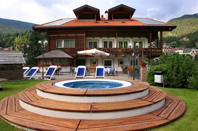 a house with a hot tub in the yard at Hotel Hell in Ortisei
