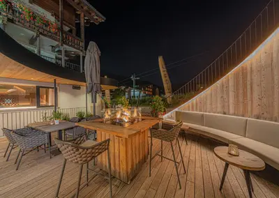 a patio with tables and chairs on a deck at night at Hotel Hell in Ortisei