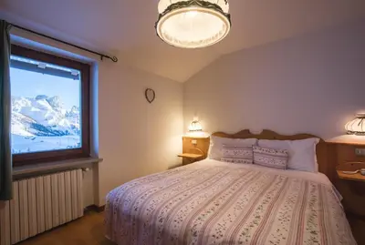a bedroom with a bed and a large window at Albergo Vezzana in Passo Rolle