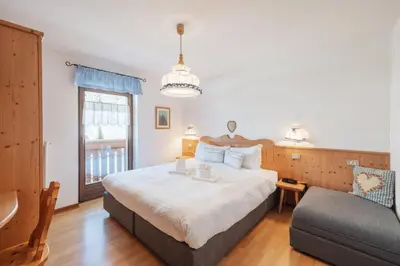 a bedroom with a large bed and a couch at Albergo Vezzana in Passo Rolle