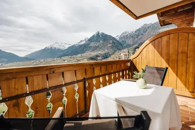 a table on a balcony with mountains in the background at Apartments Bachmair in Schenna