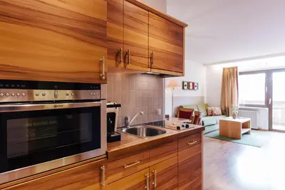 a kitchen with wooden cabinets and a stainless steel sink at Apartments Bachmair in Schenna