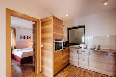 a kitchen with wooden cabinets and a bed in a room at Apartments Bachmair in Schenna