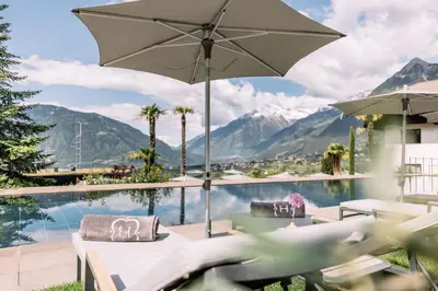 a patio with an umbrella and a swimming pool at Apartments Bachmair in Schenna