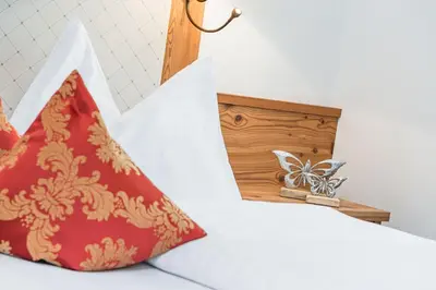 a bed with a red pillow and a box with butterflies at Amonit - Your Dolomites Home in Selva di Val Gardena