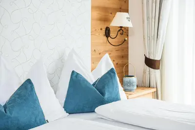 a bed with blue and white pillows on it at Amonit - Your Dolomites Home in Selva di Val Gardena