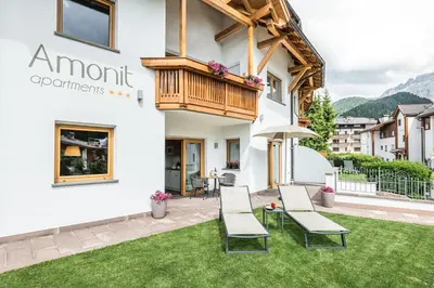 a patio with chairs and a balcony in front of a building at Amonit - Your Dolomites Home in Selva di Val Gardena
