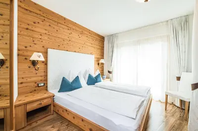 a bedroom with a bed and a wooden wall at Amonit - Your Dolomites Home in Selva di Val Gardena