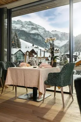 a dining room with a table and a view of a mountain at Hotel Sun Valley in Selva di Val Gardena