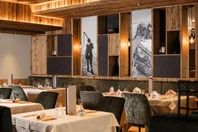 a dining room with tables and chairs and a wall with a picture at Hotel Sun Valley in Selva di Val Gardena