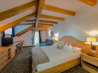 a bedroom with a large white bed and wooden ceilings at Hotel Sun Valley in Selva di Val Gardena