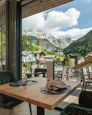 a table on a balcony with a view of a mountain at Hotel Sun Valley in Selva di Val Gardena