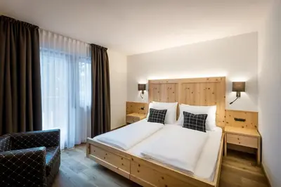 a bedroom with a large bed with a wooden headboard at Hotel Des Alpes in La Villa