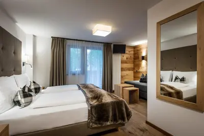 a hotel room with a large bed and a mirror at Hotel Des Alpes in La Villa