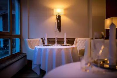 a table with a white table cloth and candles on it at Hotel Des Alpes in La Villa