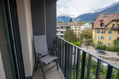 a chair sitting on a balcony looking out at the mountains at Residence Villa Hedy in Merano