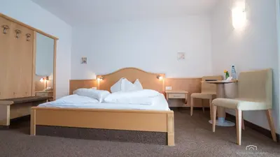 a hotel room with a bed and a chair at Kreuzstein Bed&Breakfast in Appiano sulla Strada del Vino