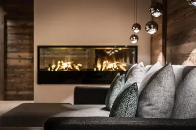 a living room with a fireplace and a couch with pillows at Chalet Roenn in Colfosco