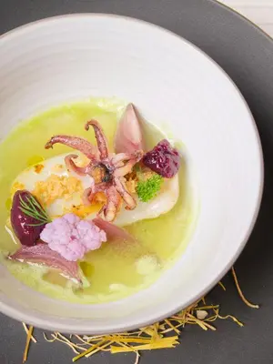 a white bowl of food with seafood and vegetables at Bonfanti Design Hotel in Chienes