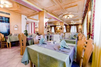 a dining room with tables and chairs in a restaurant at Albergo Eden in Fiera di Primiero