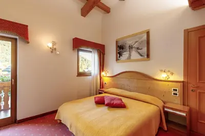 a bedroom with a bed with a red pillow on it at Albergo Eden in Fiera di Primiero