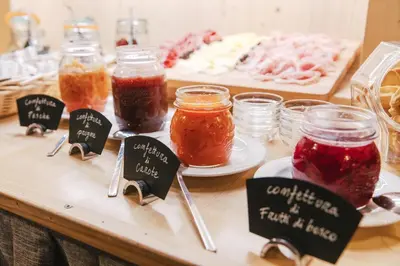 a table topped with jars of jam and jars of food at Albergo Eden in Fiera di Primiero