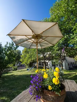 a picnic table with an umbrella and flowers in a basket at Gasthof Zur Sonne in Laion