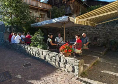 a group of people sitting at a table under an umbrella at Gasthof Zur Sonne in Laion