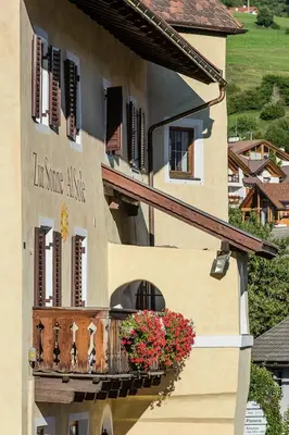 a building with a balcony with flowers on it at Gasthof Zur Sonne in Laion