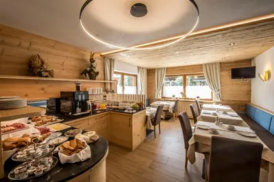 a restaurant with tables and chairs with food on display at Garnì Lasteis B&B - apartments in La Villa