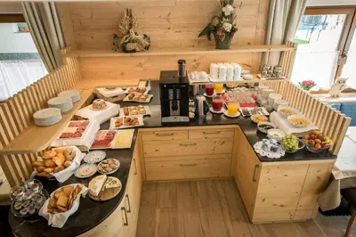 a breakfast table in a kitchen with food on it at Garnì Lasteis B&B - apartments in La Villa
