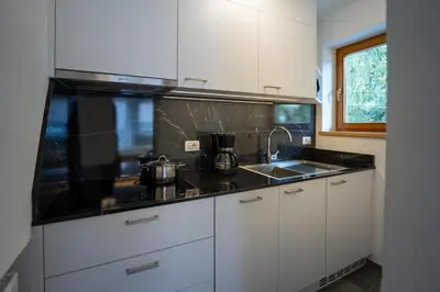 a kitchen with white cabinets and a black counter top at Garnì Lasteis B&B - apartments in La Villa