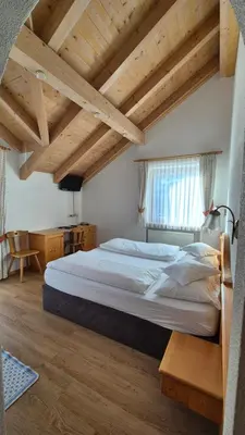 a large bed in a room with wooden ceilings at Garnì Lasteis B&B - apartments in La Villa