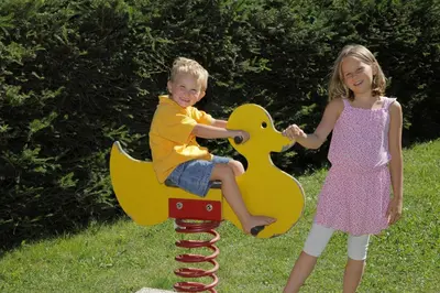 a boy and a girl playing on a toy horse on a playground at Vitalhotel Rainer in Ultimo