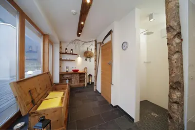 a bathroom with a bench and a shower and a sink at Vitalhotel Rainer in Ultimo