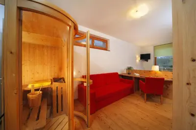 a living room with a red couch and a desk at Vitalhotel Rainer in Ultimo