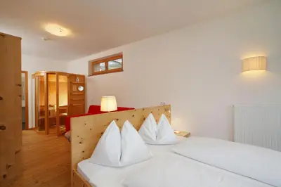 a bedroom with a white bed with white pillows at Vitalhotel Rainer in Ultimo