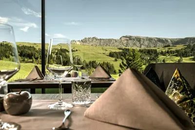 a table with wine glasses and a view of the mountains at Hotel Schmung in Alpe di Siusi