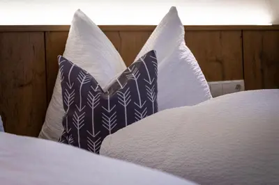 a bed with blue and white pillows on it at Chalet Morin in San Martino in Badia