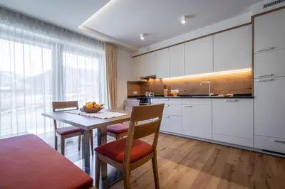 a kitchen with white cabinets and a table with chairs at Chalet Morin in San Martino in Badia